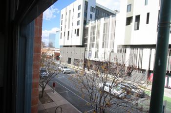 A view of a street from a window with cars and buildings.