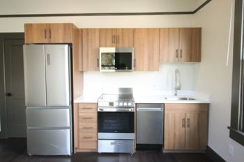 A kitchen with a refrigerator, oven, and microwave.