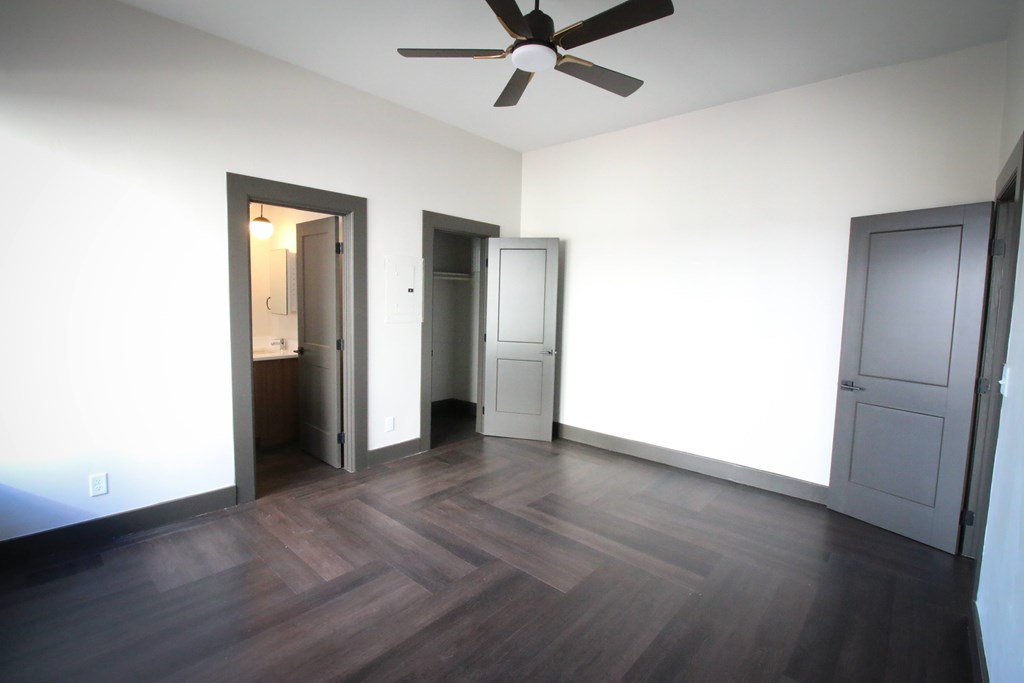 A room with a ceiling fan and wooden flooring.