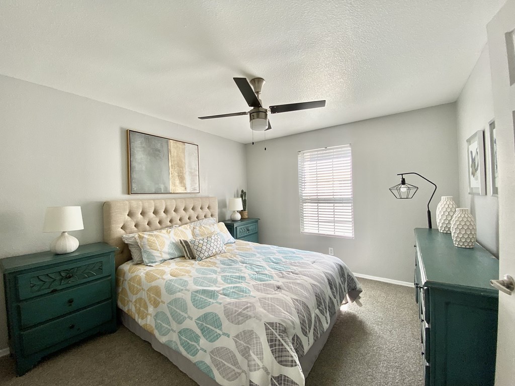 A bedroom with a bed, nightstand, and a ceiling fan.