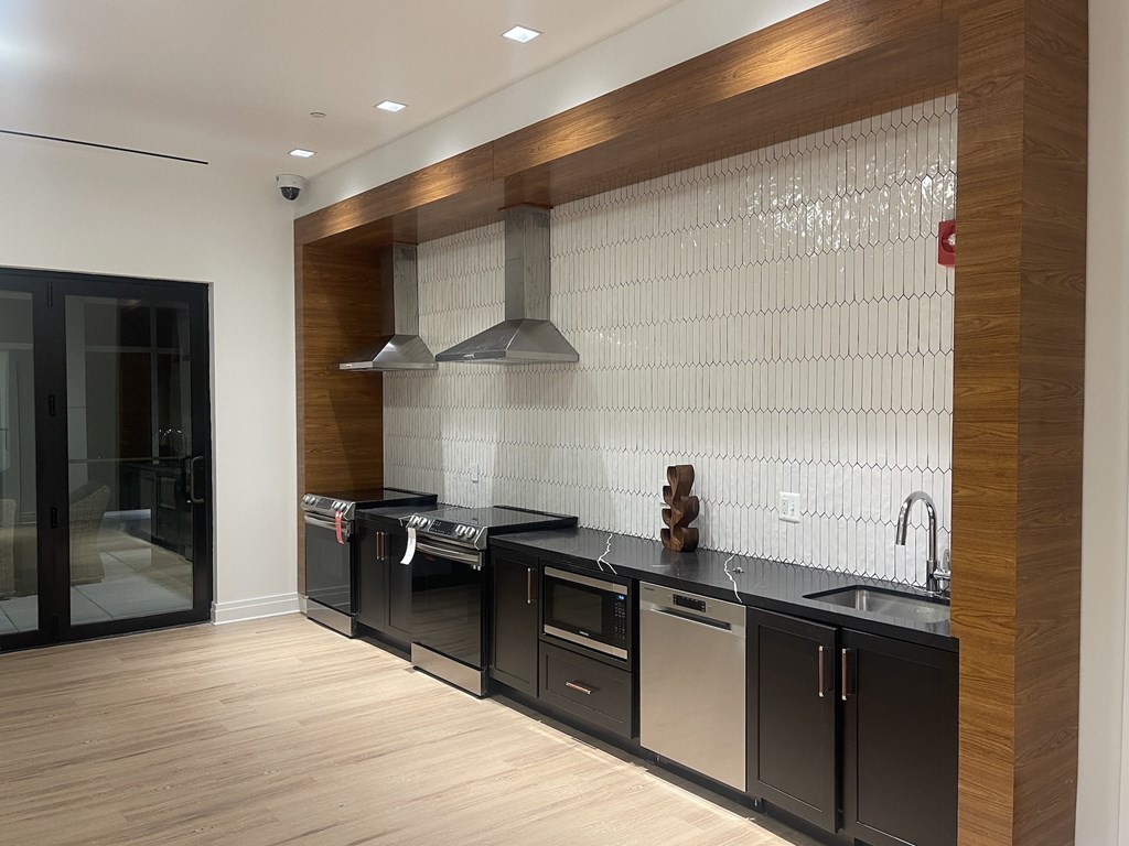 A modern kitchen with black cabinets and a wooden accent wall.