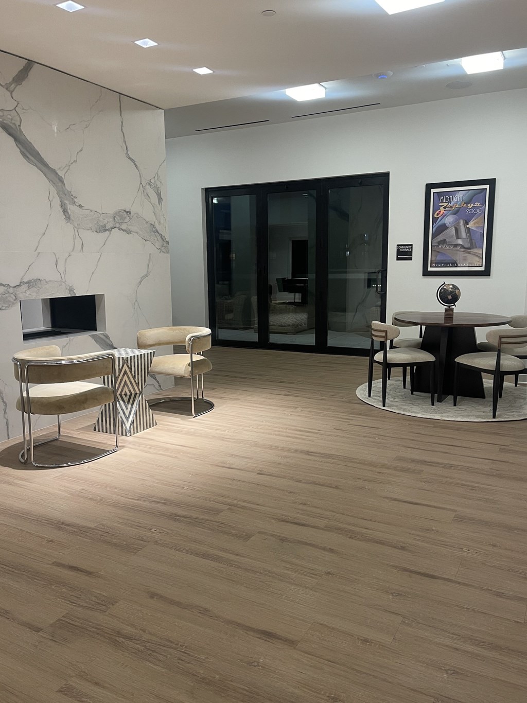 A modern living room with a marble fireplace and a glass door.