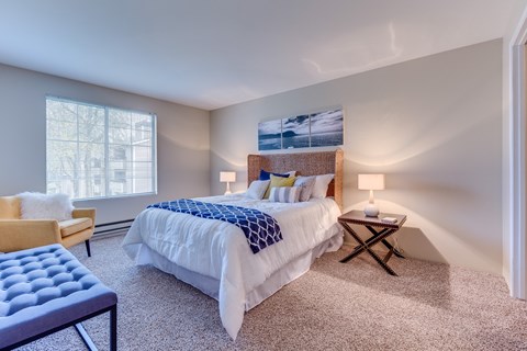A bedroom with a large bed and a chair.