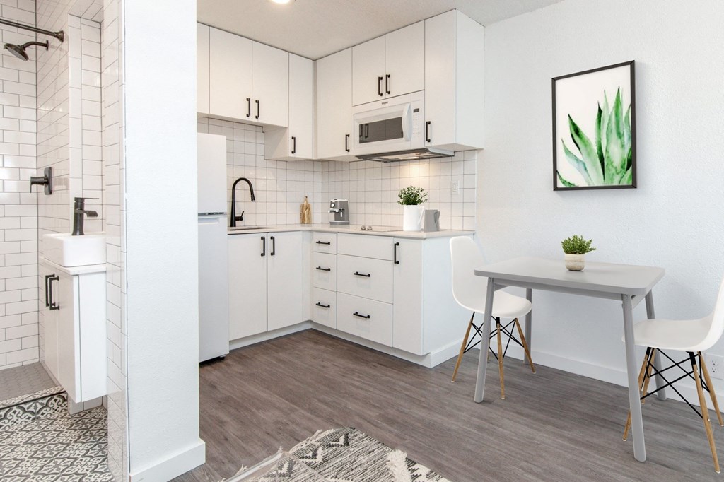 a kitchen with white cabinets and a white dining table with two white chairs