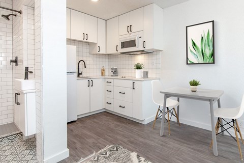 a kitchen with white cabinets and a white dining table with two white chairs
