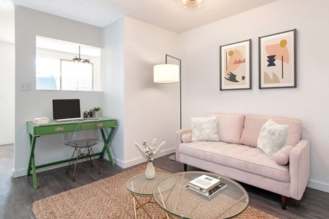 a living room with a green desk and a pink couch