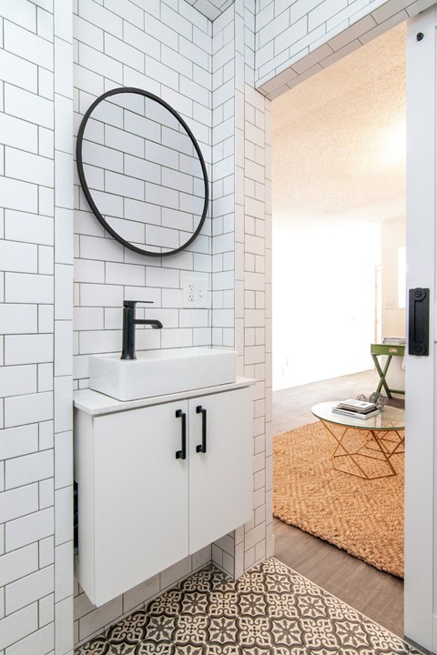 a small bathroom with white subway tile and a white sink with a black faucet