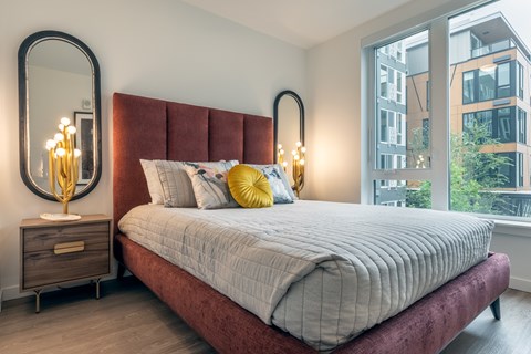 A bedroom with a large bed, a mirror, and a nightstand with a candle.