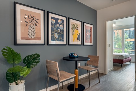 A dining area with a table, chairs and pictures on the wall.