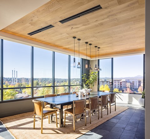 A dining room with a large table and chairs with a view of the city.