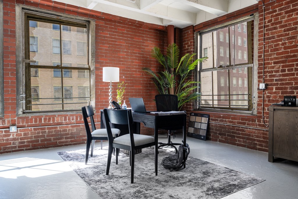 a dining room with a table and chairs in front of a brick wall