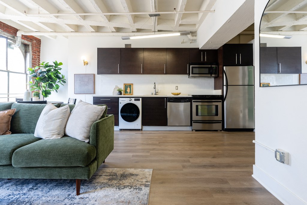 a living room with a couch and a kitchen with stainless steel appliances