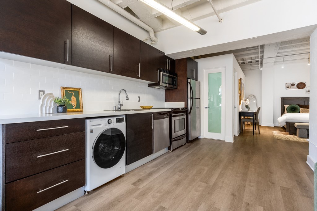 a kitchen with a washer and dryer and a living room with a door