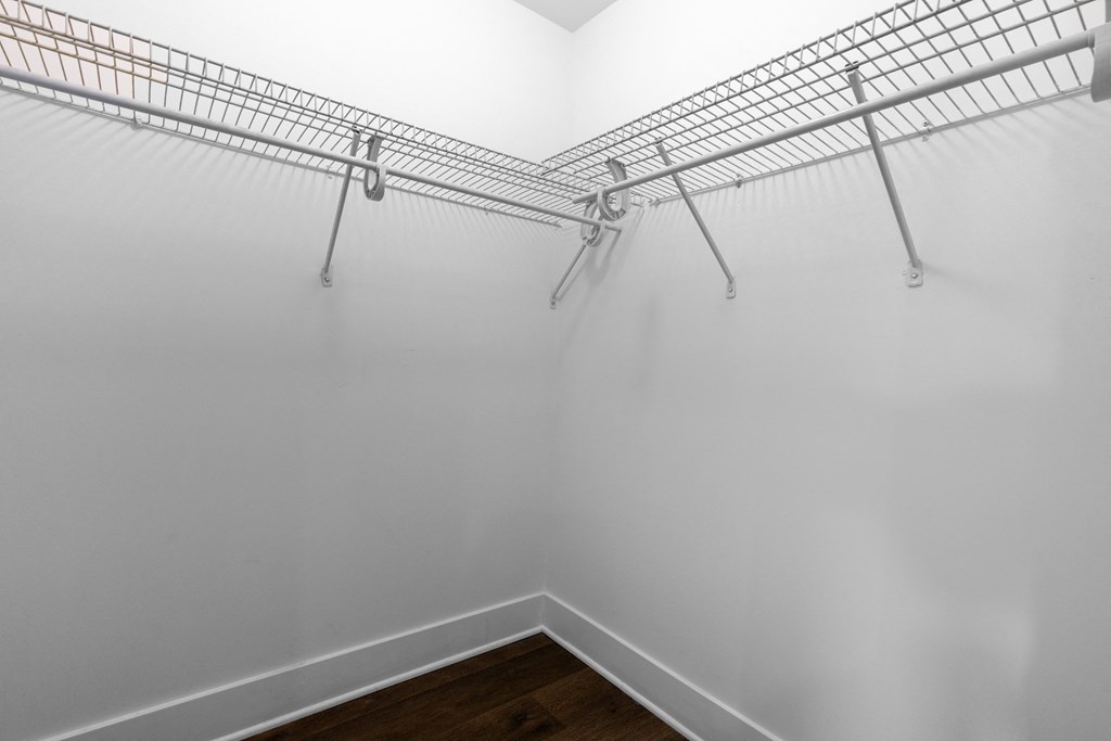 an empty room with white walls and a closet with metal shelves
