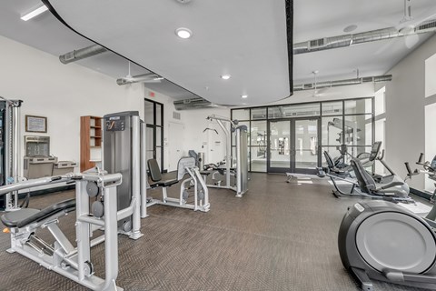 A gym with a variety of equipment including treadmills, weights, and exercise machines.