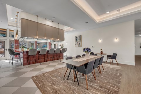 A dining room with a checkered floor and a long table with chairs.