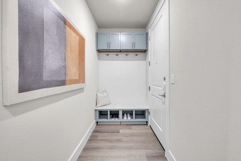 A hallway with a bench and a painting on the wall.