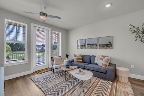 A living room with a grey couch, a rug, and a ceiling fan.