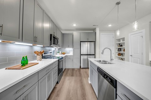 A modern kitchen with stainless steel appliances and wooden floors.