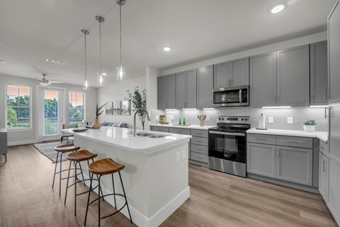 A modern kitchen with a white island and stainless steel appliances.
