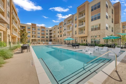 A large swimming pool in front of apartment buildings.