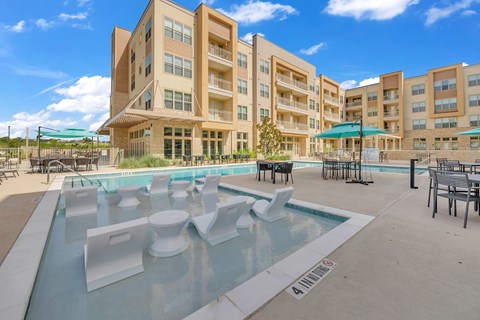 A large apartment complex with a pool in the foreground.