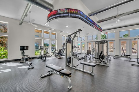 A gym with a variety of equipment including treadmills, weights, and exercise machines.