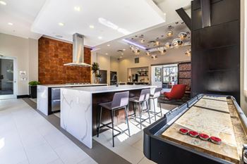 A billiard table is in the middle of a kitchen and dining area.