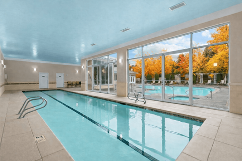 A large indoor swimming pool with a view of the outdoors through the windows.