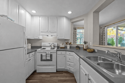 A white kitchen with a stove top oven and a refrigerator.