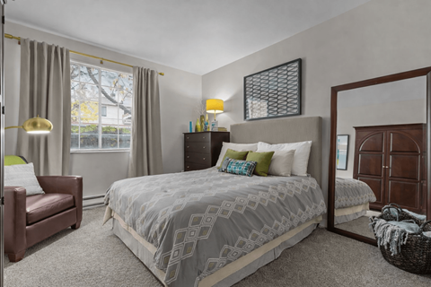 A bedroom with a large bed and a chair.