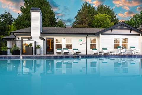 a swimming pool in front of a white house with a pool