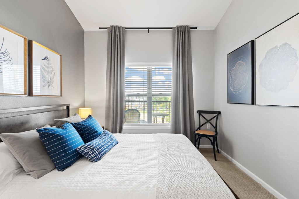 A bedroom with a large bed and a chair by the window.