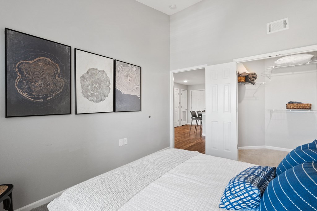 A bedroom with a white bed and two framed artworks on the wall.