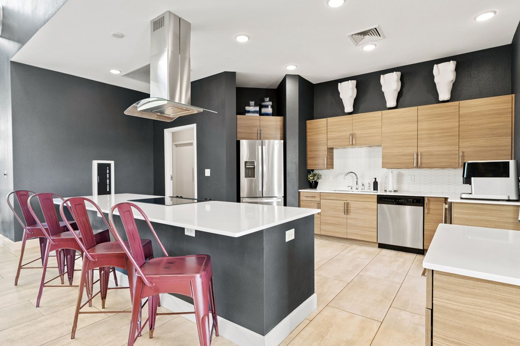 A modern kitchen with red chairs and a white island.