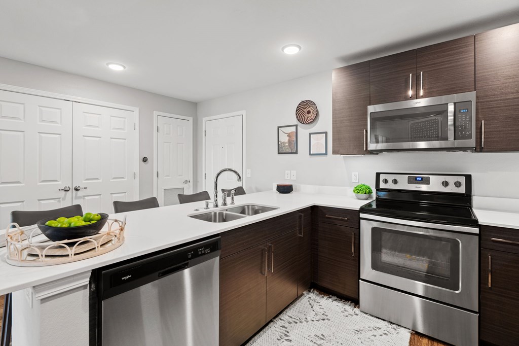 A modern kitchen with dark wood cabinets and stainless steel appliances.