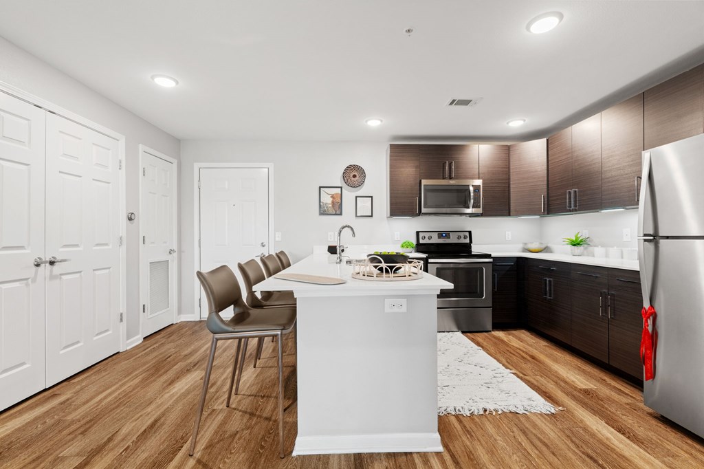 A kitchen with a white island and brown cabinets.