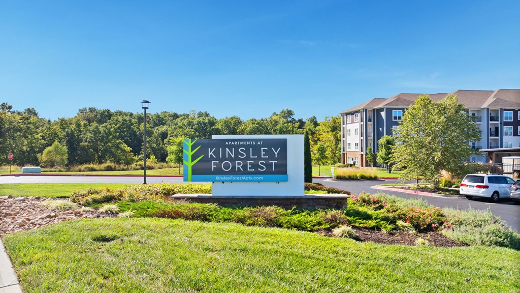 A sign for Kinsley Forest in front of a building.