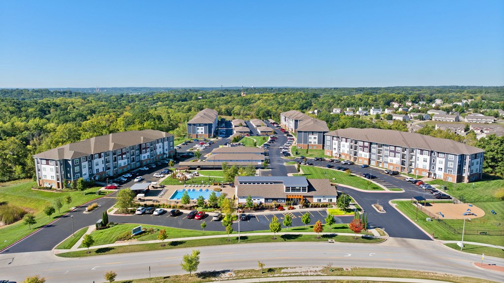 A large apartment complex with a swimming pool and a spacious parking lot.