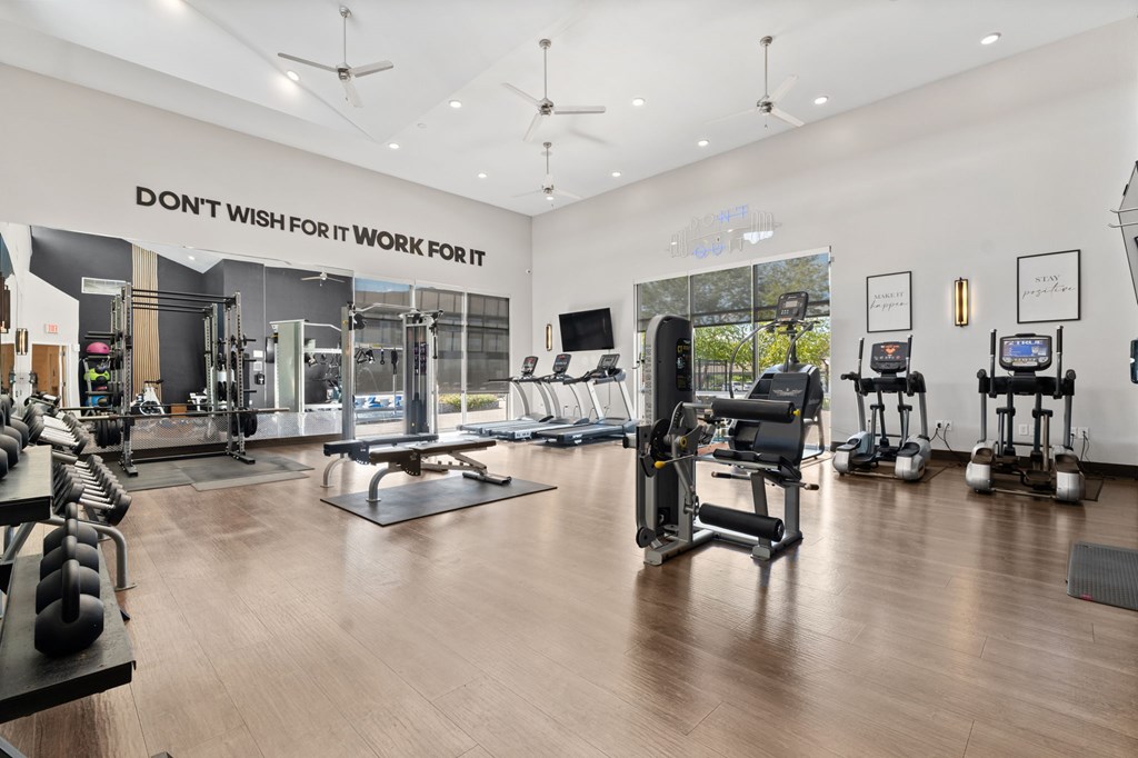 A gym with a variety of equipment including treadmills, weights, and exercise machines.