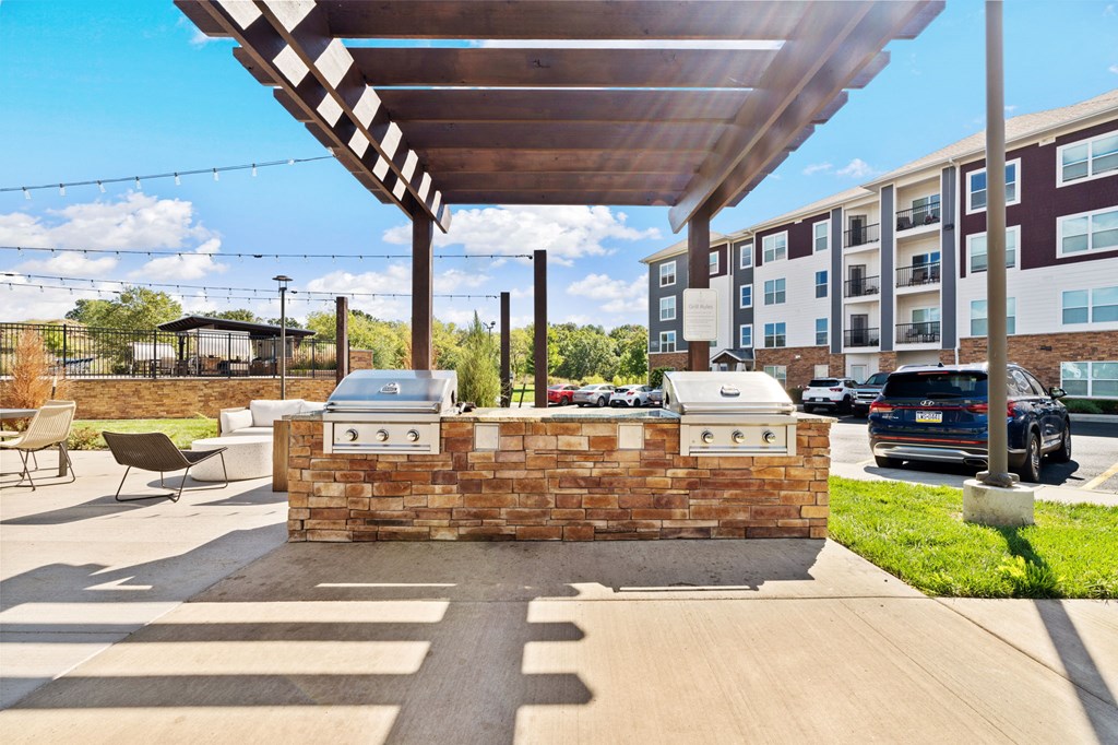 A brick structure with a grill on top is in the foreground of a sunny outdoor area.