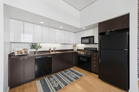 A kitchen with brown cabinets and a black refrigerator.