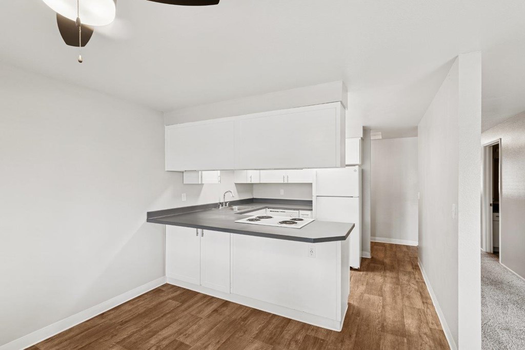 Kitchen A modern kitchen with white cabinets and a wooden floor.