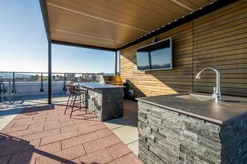 A modern outdoor kitchen with a stone counter and a bar stool.