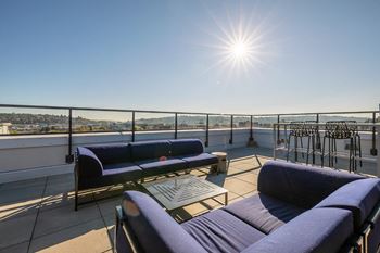 A sunny day on a rooftop patio with two chairs and a table.