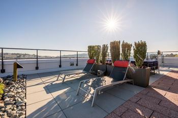A sunny day at the rooftop with chairs and a railing.