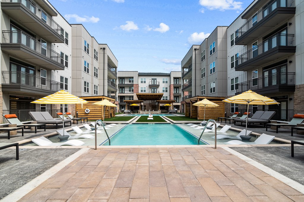 an outdoor pool with lounge chairs and umbrellas at the bradley braddock road