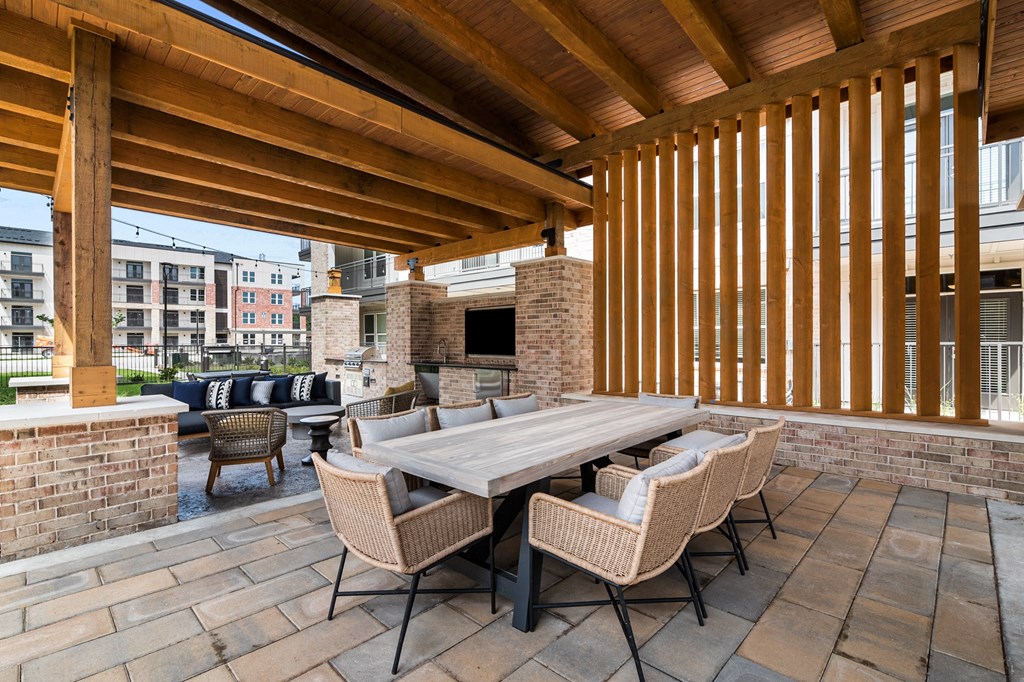 a covered patio with a large wooden table and chairs