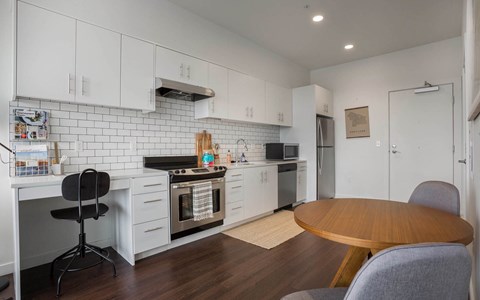 A kitchen with white cabinets and a black chair.