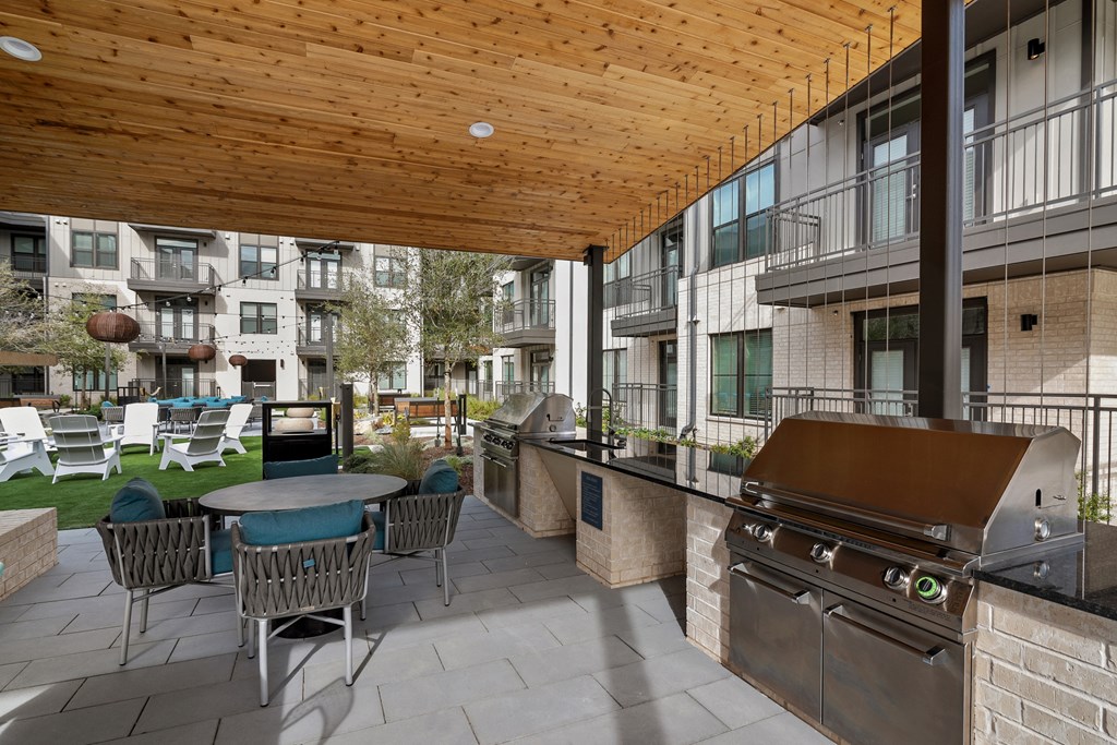 a patio with a barbecue grill and a table with chairs
